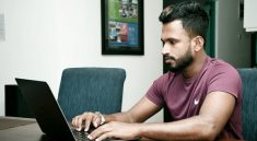 A person working on their laptop in a workspace.