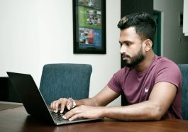 A person working on their laptop in a workspace.