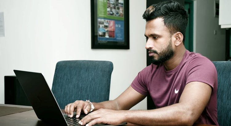 A person working on their laptop in a workspace.